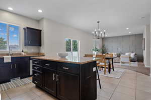 Kitchen with recessed lighting, light stone countertops, a breakfast bar, a center island, and light tile patterned flooring