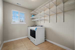 Laundry room featuring light tile patterned floors and washing machine and dryer