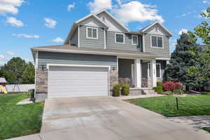 Craftsman-style house featuring a front lawn, board and batten siding, stone siding, and concrete driveway