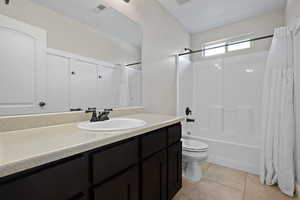 Full bath featuring shower / tub combo with curtain, light tile patterned flooring, and vanity