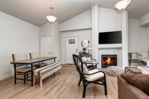 Dining area featuring light wood-type flooring, high vaulted ceiling, and a fireplace