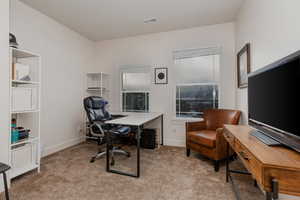 Home office with light carpet and baseboards