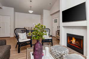 Living room featuring light wood-style flooring, a fireplace, and lofted ceiling