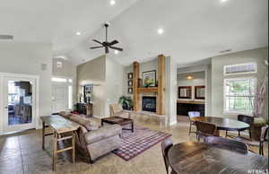 Living area featuring high vaulted ceiling, a ceiling fan, a large fireplace, and recessed lighting
