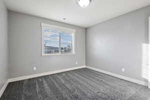 Carpeted spare room featuring baseboards