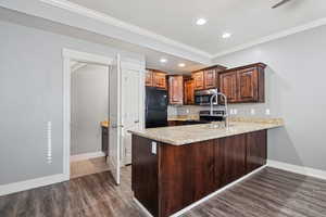 Kitchen with ornamental molding, light stone countertops, stainless steel appliances, recessed lighting, and a peninsula