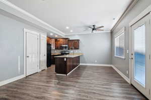 Kitchen with a peninsula, recessed lighting, light stone counters, dark wood finished floors, and crown molding