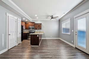 Kitchen featuring crown molding, appliances with stainless steel finishes, light stone countertops, recessed lighting, and dark wood-style floors
