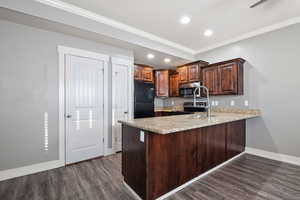 Kitchen with ornamental molding, stainless steel appliances, a peninsula, dark brown cabinets, and dark wood-style floors
