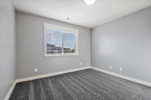 Carpeted spare room featuring baseboards