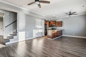 Kitchen with a ceiling fan, crown molding, a peninsula, dark wood-type flooring, and open floor plan