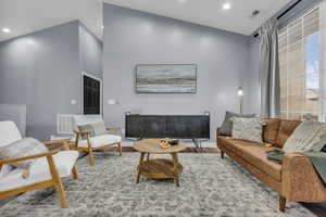 Living room featuring recessed lighting, a high ceiling, and wood finished floors