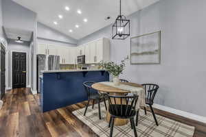 Dining space featuring dark wood-style floors, recessed lighting, and high vaulted ceiling