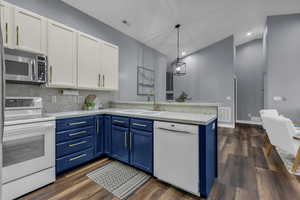 Kitchen with blue cabinetry, white appliances, white cabinetry, dark wood-style flooring, and recessed lighting