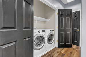 Laundry room featuring wood finished floors and washer and clothes dryer