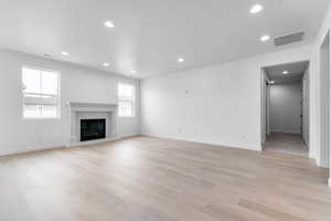 Unfurnished living room with recessed lighting, light wood finished floors, and a glass covered fireplace