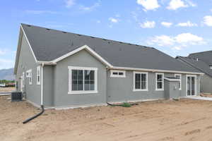 Back of house featuring a shingled roof and stucco siding