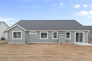 Back of property with stucco siding, a shingled roof, and a patio
