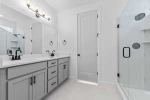 Bathroom featuring a shower stall, double vanity, and light tile patterned flooring
