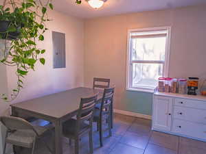 Tiled dining space with electric panel and baseboards