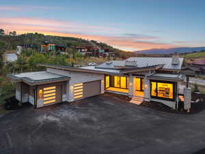 Contemporary home featuring a standing seam roof, a garage, a metal roof, stone siding, and driveway
