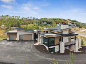 Contemporary house with a standing seam roof, a metal roof, asphalt driveway, an attached garage, and a sunroom