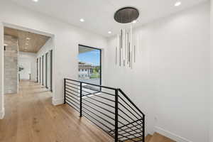 Hall with an upstairs landing, recessed lighting, and light wood-type flooring