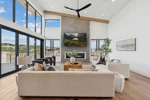 Living area featuring a large fireplace, light wood-style flooring, high vaulted ceiling, and recessed lighting