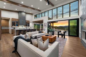 Living area with beam ceiling, light wood-style flooring, recessed lighting, and a towering ceiling