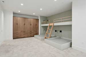 Unfurnished bedroom with recessed lighting, light colored carpet, and wood walls
