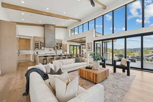 Living room featuring beamed ceiling, light wood-type flooring, recessed lighting, a mountain view, and a high ceiling