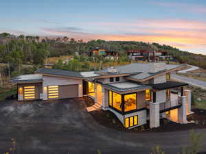 Modern home featuring a standing seam roof, driveway, an attached garage, a metal roof, and stone siding