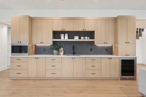 Kitchen featuring light brown cabinetry, open shelves, wine cooler, and light wood-type flooring