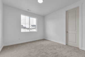Empty room featuring light colored carpet and baseboards