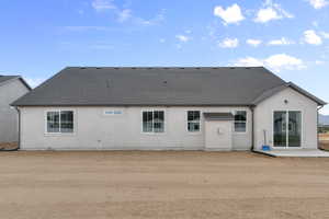 Back of property featuring a shingled roof, a patio, and stucco siding