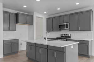 Kitchen with decorative backsplash, gray cabinets, light stone counters, dark wood-style floors, and recessed lighting