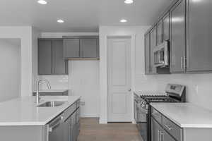 Kitchen featuring gray cabinetry, stainless steel appliances, decorative backsplash, recessed lighting, and light stone counters