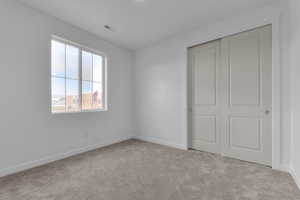 Unfurnished bedroom featuring light carpet and a closet
