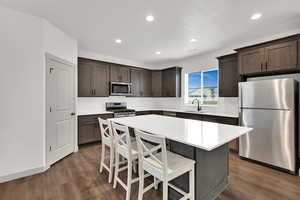 Kitchen with a kitchen breakfast bar, stainless steel appliances, a kitchen island, backsplash, and recessed lighting