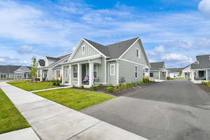 Modern inspired farmhouse with board and batten siding, covered porch, a residential view, roof with shingles, and a front lawn