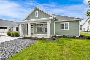 View of front of house with board and batten siding, a porch, a front lawn, and roof with shingles
