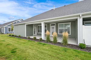 Rear view of property with roof with shingles, a lawn, and covered porch