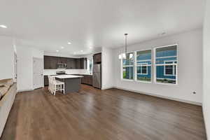 Kitchen with open floor plan, a breakfast bar, light countertops, recessed lighting, and decorative light fixtures