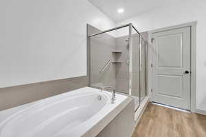 Bathroom featuring a garden tub, a shower stall, and light wood-type flooring