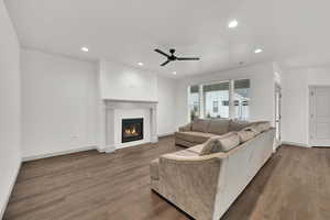 Living area with recessed lighting, dark wood-style floors, a ceiling fan, and a glass covered fireplace