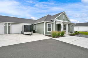 View of front of home featuring concrete driveway, a shingled roof, a garage, covered porch, and board and batten siding