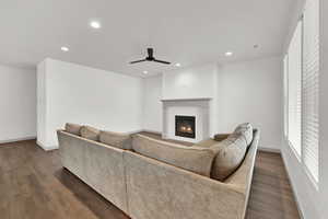 Living room with a glass covered fireplace, dark wood-type flooring, recessed lighting, and a ceiling fan