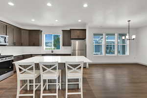 Kitchen with decorative backsplash, appliances with stainless steel finishes, dark brown cabinetry, a kitchen breakfast bar, and recessed lighting