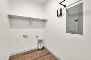 Washroom with electric panel, electric dryer hookup, wood finished floors, and washer hookup