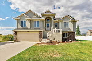View of front facade with stone siding, stucco siding, concrete driveway, and stairway